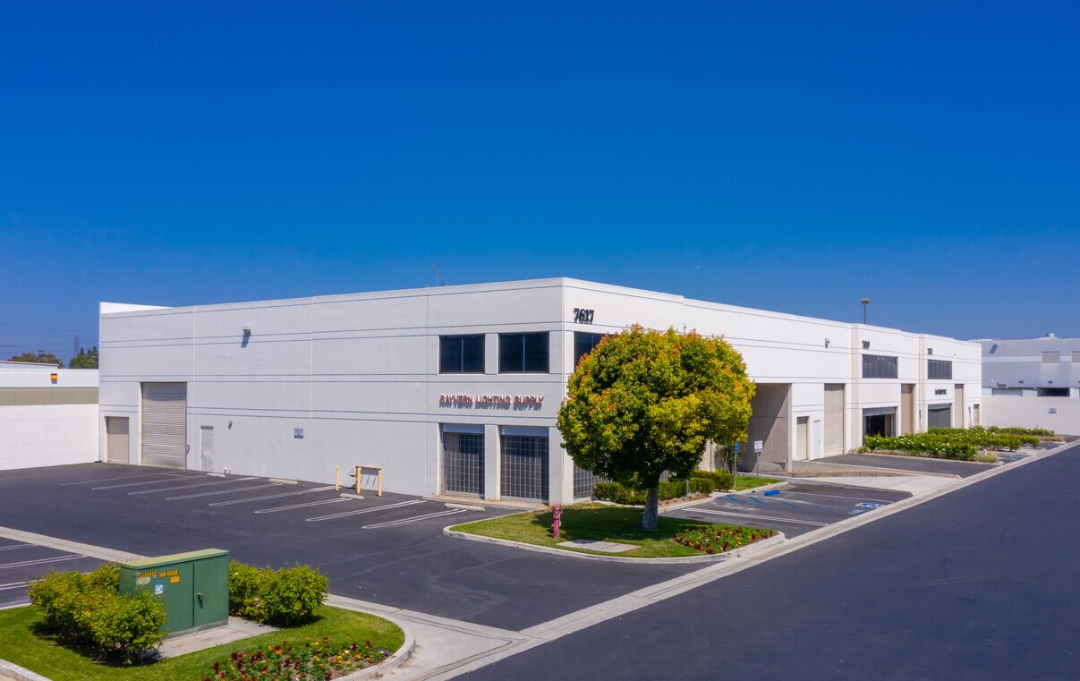 Corner building elevation with Rayvern Lighting Supply signage and tenant parking