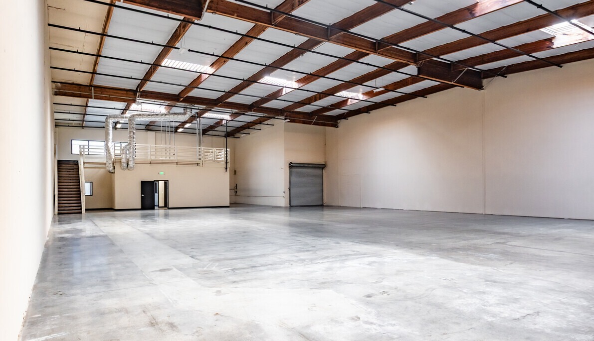 Vacant warehouse with wood truss ceiling, mezzanine and grade-level roll-up door
