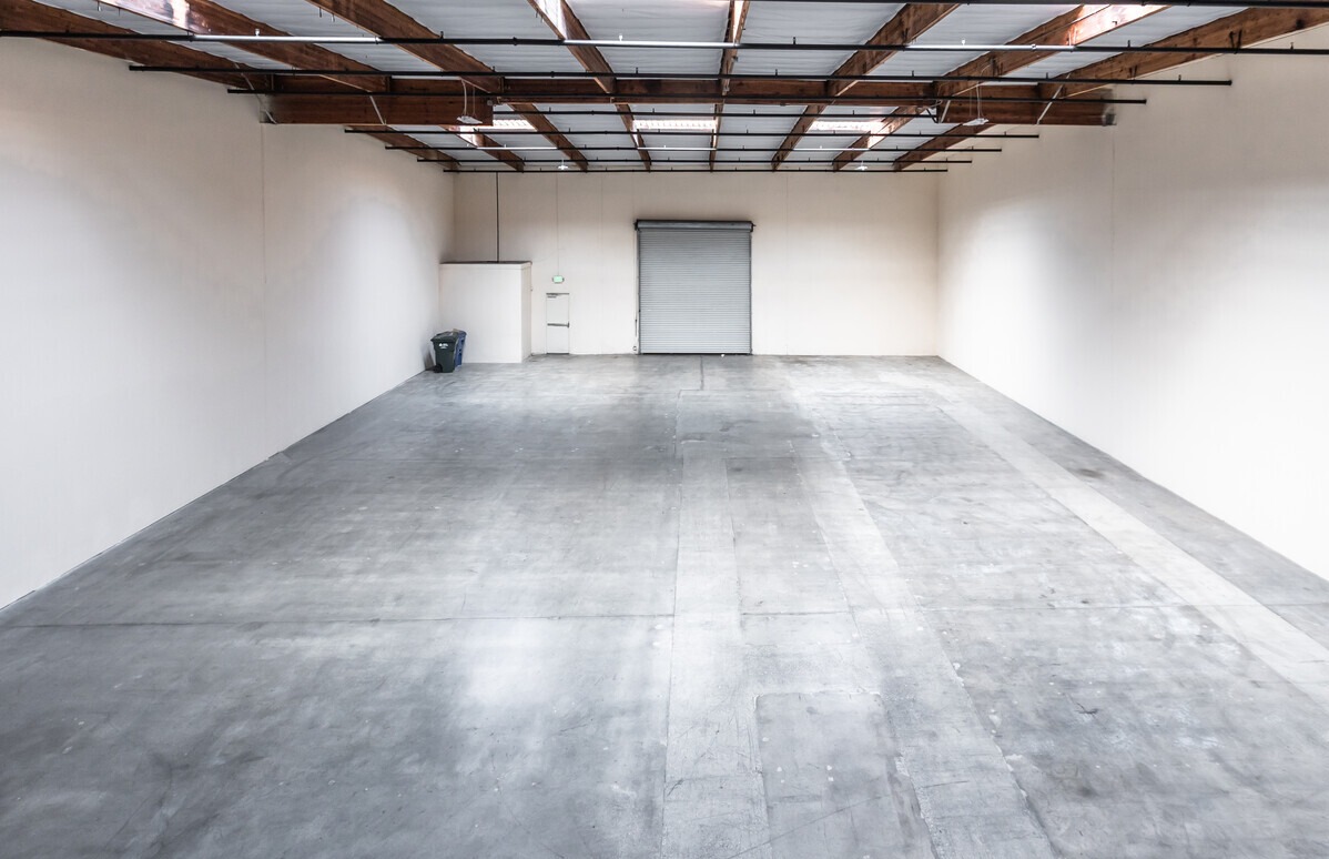 Vacant warehouse unit with grade-level roll-up door and sealed concrete floor